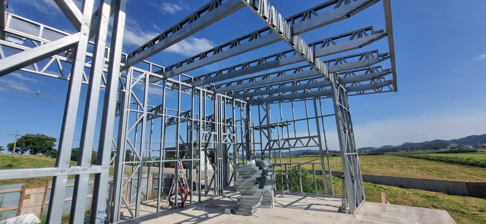 Estrutura em Light Steel Frame com vigas treliçadas sobre laje, com campos e montanhas ao fundo